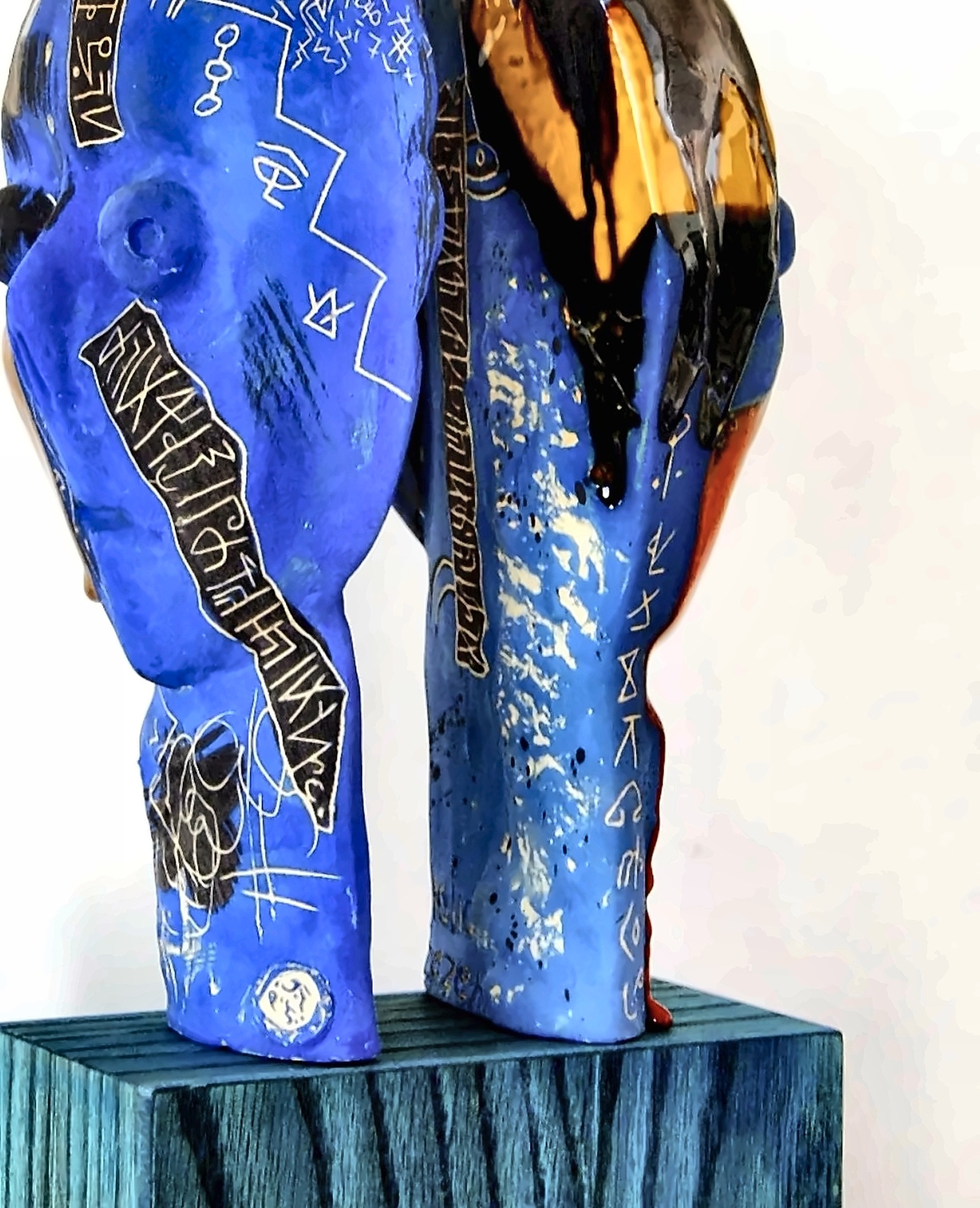 Two tall blue-glazed ceramic figures covered in incised marks.
