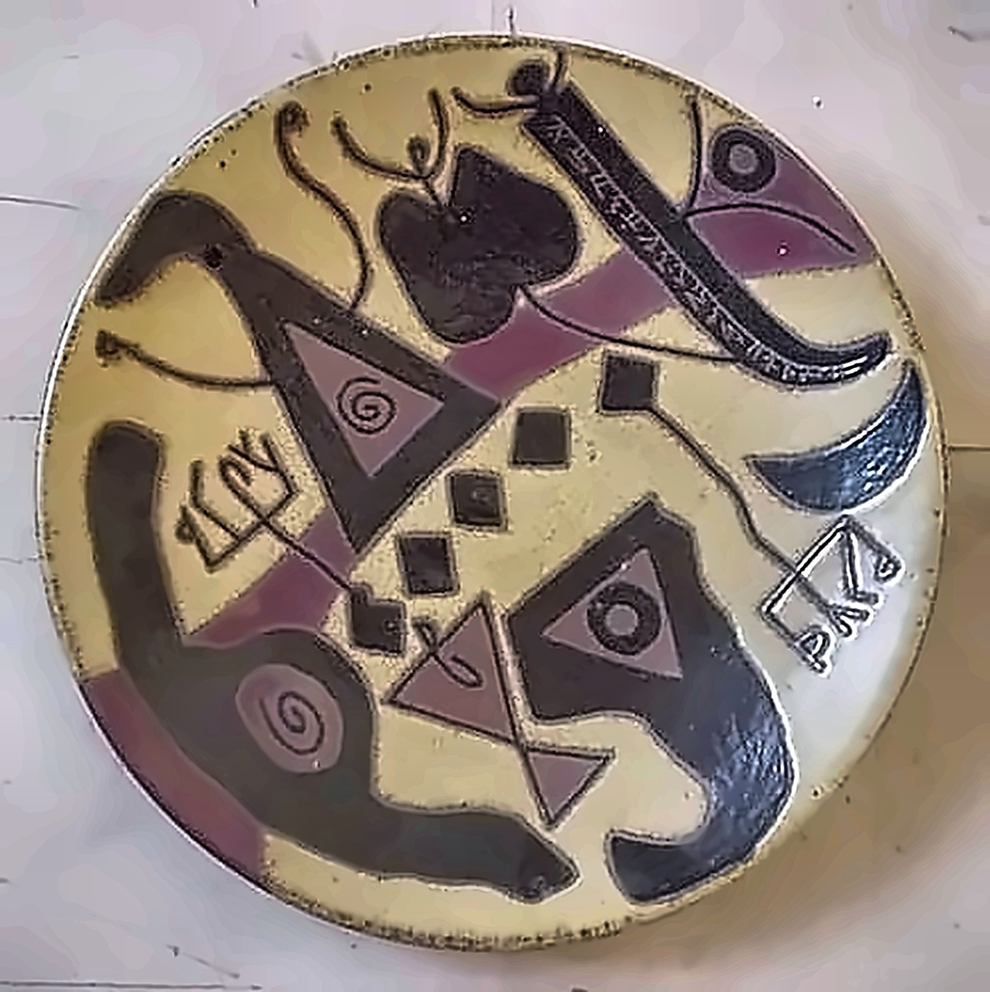 A plate with black hooks and triangles over dusty pink, spirals and small script marks between them.