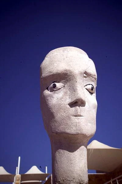 Cabeza esculpida clara iluminada por el sol, contra un cielo azul intenso.