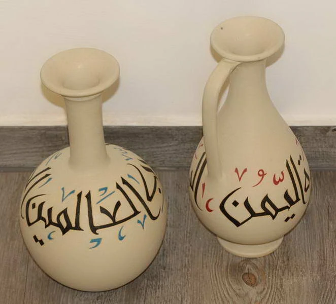 جرتان كريميتان عليهما خط عربي أسود مع علامات زرقاء وحمراء.