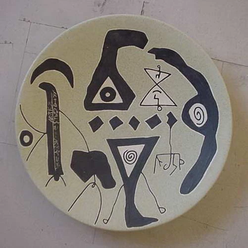 صحن فاتح عليه خطاطيف ومثلثات سوداء وحلزونات وصف من المعينات الصغيرة.