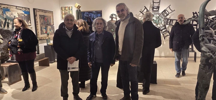 ثلاثة رجال يقفون معا إلى جوار الأعمال في قاعة العرض.