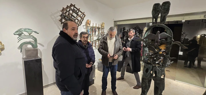 ضيوف يقفون إلى جوار شخصية برونزية طويلة ذات رأسين، ترافقها طيور.