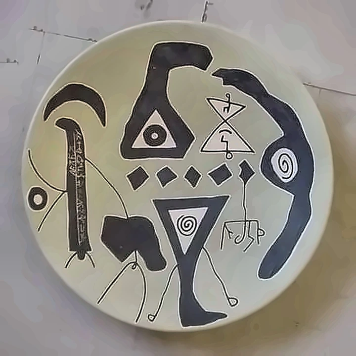 Plato claro con ganchos, triángulos, espirales negros y una hilera de pequeños rombos.