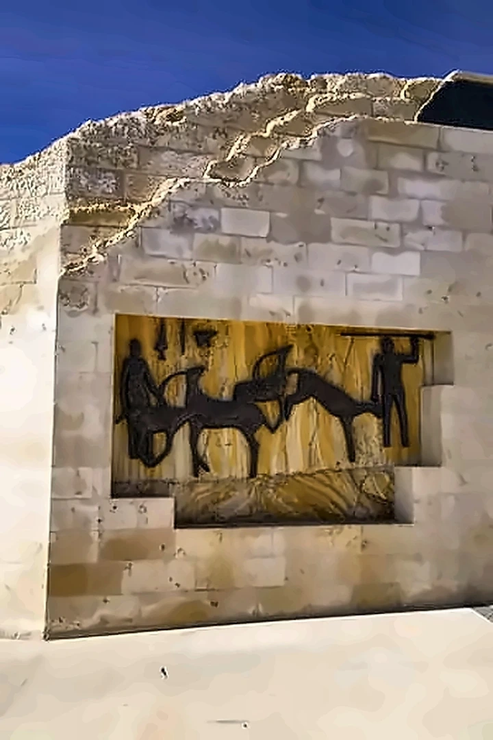 العمل نفسه من مسافة أبعد، ظاهرا كجزء من واجهة مبنى حجري تحت سماء زرقاء داكنة.