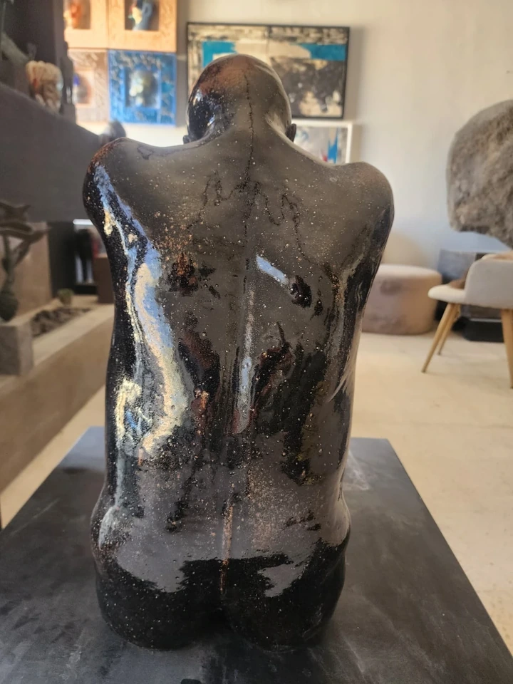 La espalda de la figura sentada, con acumulaciones de esmalte negro sobre la arcilla roja.