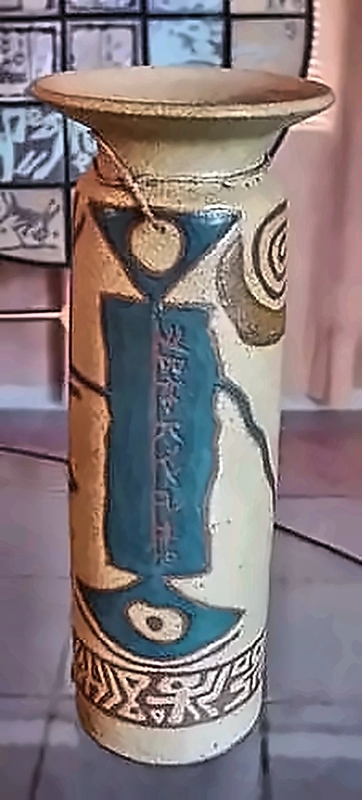 Jarrón cilíndrico, con un panel turquesa de escritura sobre gres claro.