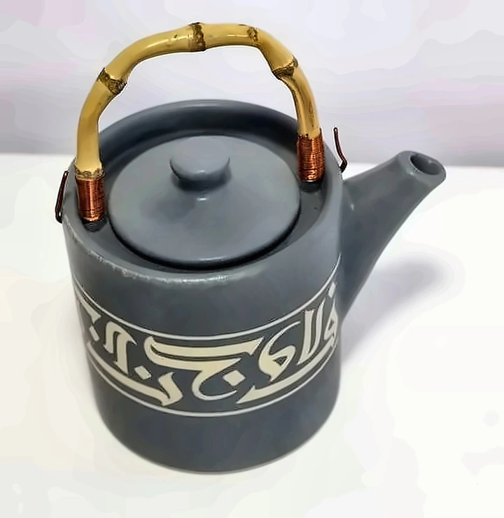 Tetera gris con asa de bambú, una banda de caligrafía cúfica clara alrededor del cuerpo.