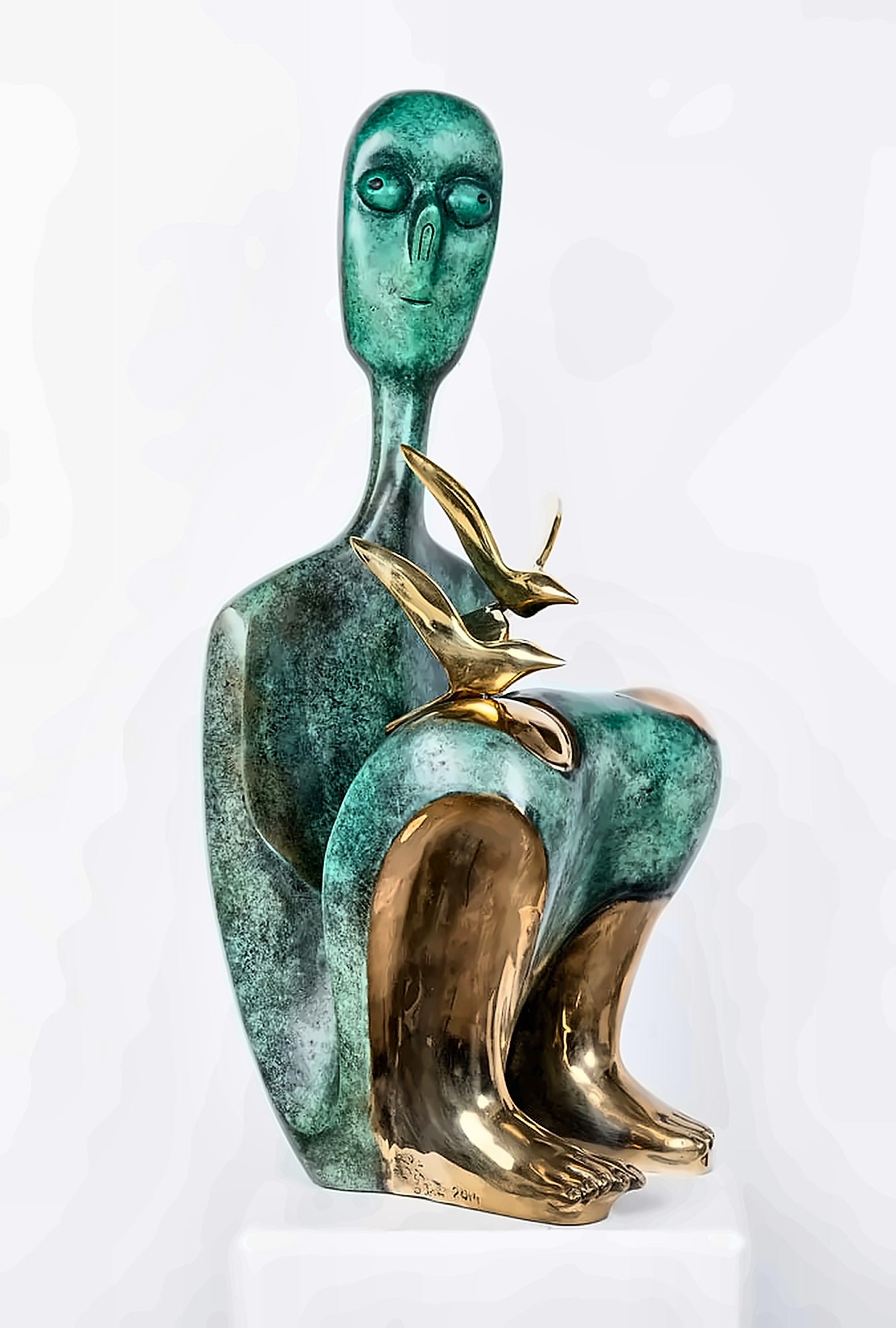 A seated bronze figure in green patina with polished golden feet and shins, two burnished birds resting on the knee.