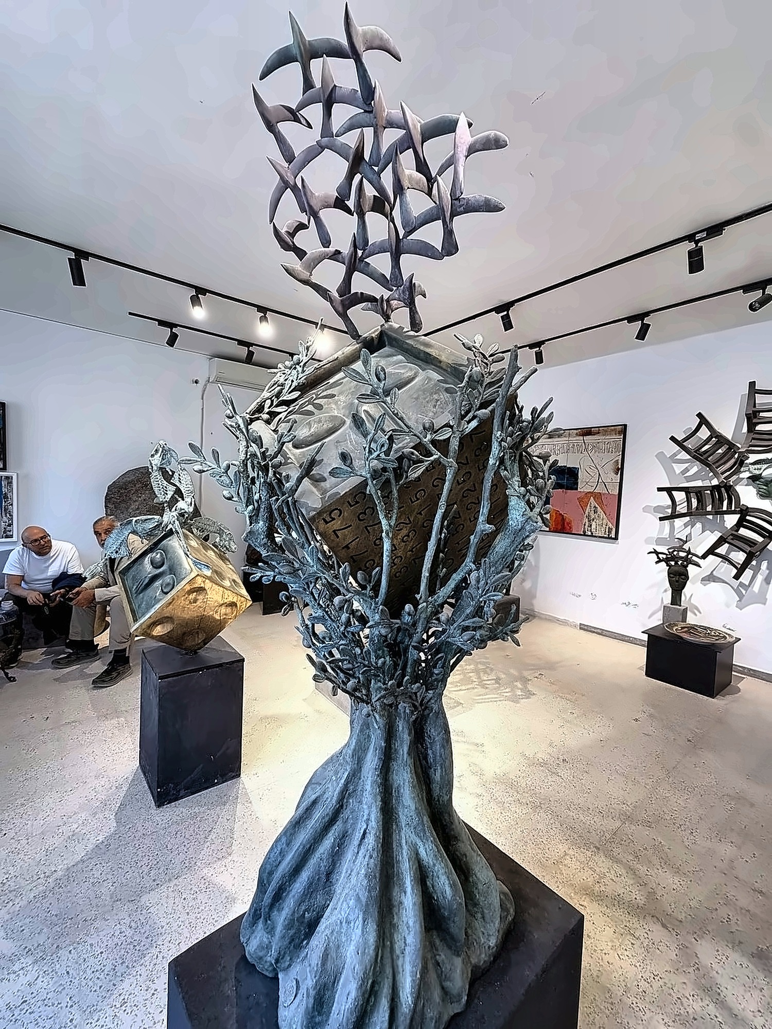 Un árbol de bronce del que se elevan pájaros.