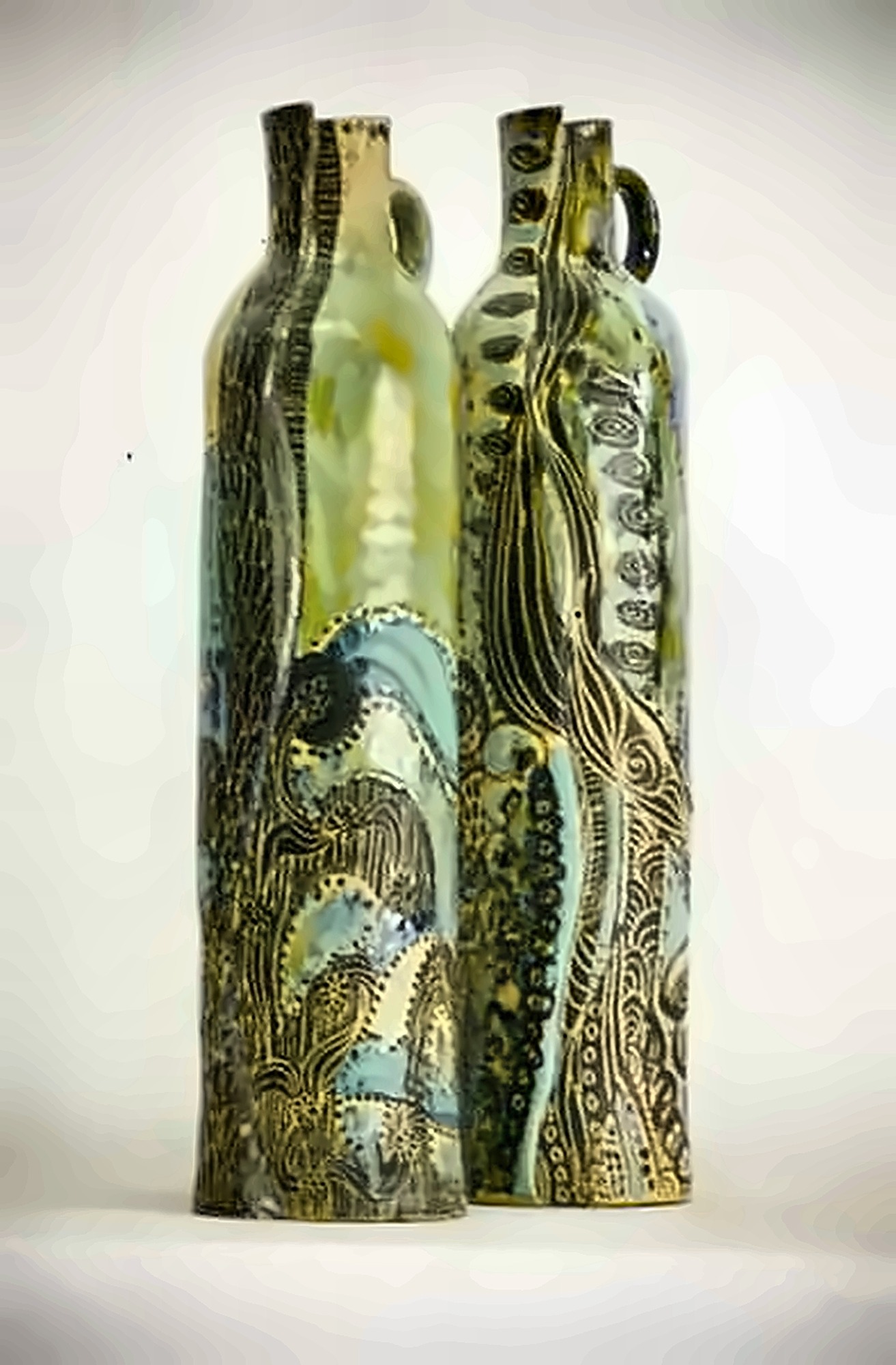 Four tall green bottles, deeply carved and glazed in mottled green and blue.