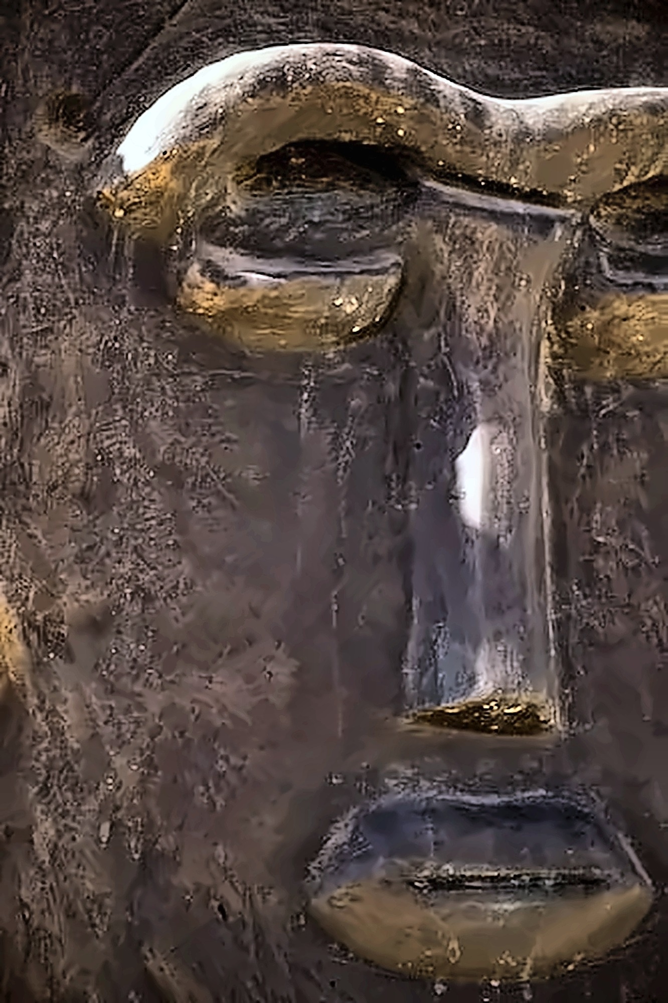 A single dark panel: two square eye forms above a mouth, on a carved stone ground.